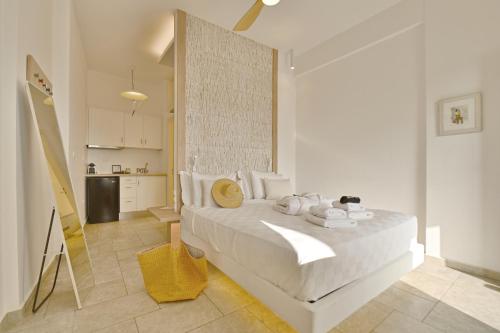 a bedroom with a white bed and a kitchen at Kallichoron Art Boutique Hotel in Astypalaia Town