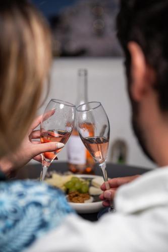 two people holding wine glasses in front of a plate of food at Kallichoron Art Boutique Hotel in Astypalaia Town