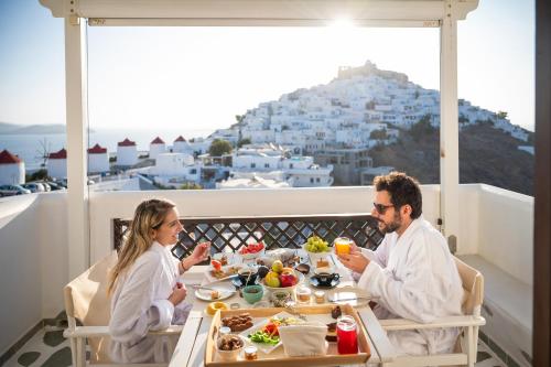 un homme et une femme assis à une table mangeant de la nourriture dans l'établissement Kallichoron Art Boutique Hotel, à Astypalée