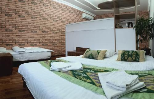 - 2 lits dans une chambre avec un mur en briques dans l'établissement House4you, à Tachkent