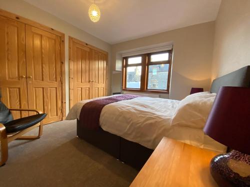 um quarto com uma cama, uma janela e uma cadeira em Lyngarrie em Dufftown