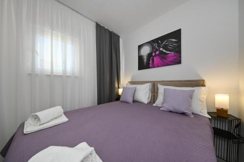 a bedroom with a large bed with purple sheets at Luxury Apartment Gloria Old Town Zadar with Sea View in Zadar