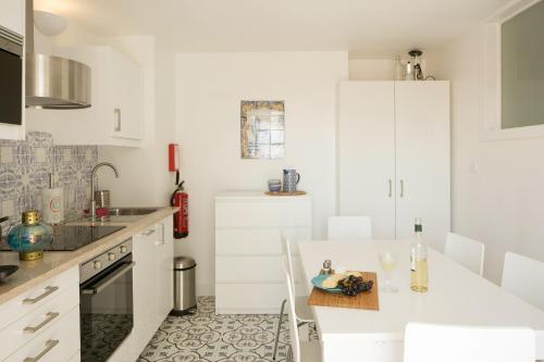 uma cozinha branca com armários brancos e um lavatório em Apartamento com varanda no centro de Lisboa, TTL269 em Lisboa