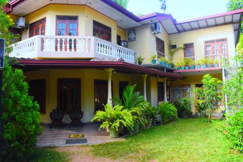 a house with a balcony and a yard at Lodge In The Valley Udawalawa in Udawalawe