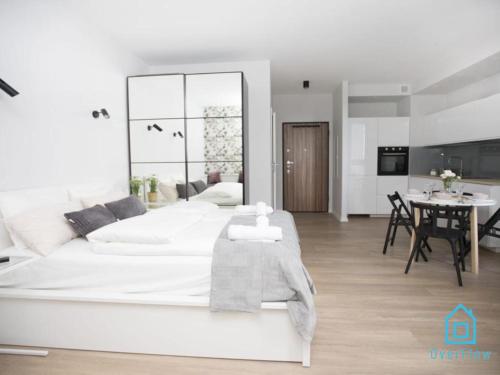 Un dormitorio blanco con una gran cama blanca y una mesa en White Apartment, en Gdansk