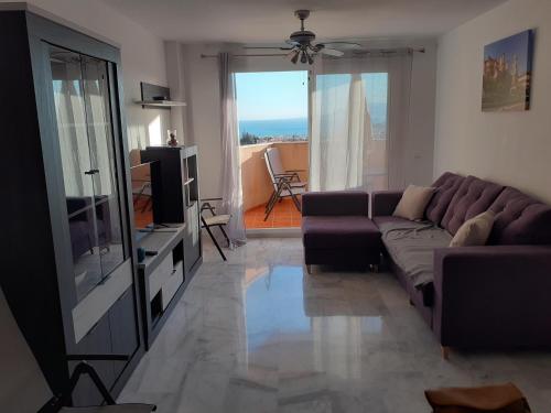 ein Wohnzimmer mit einem Sofa und einem TV in der Unterkunft Appartement avec vue sur baie de Malaga in Torre de Benagalbón