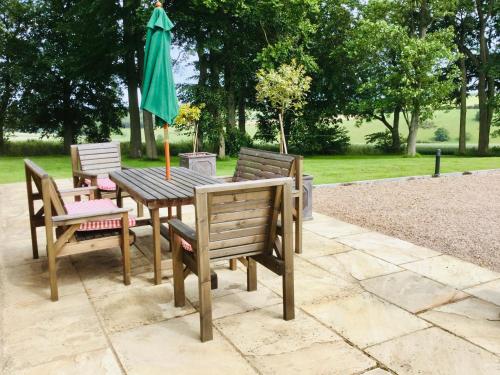 une table et des chaises en bois avec un parasol vert dans l'établissement Cowdale Cottage, à York