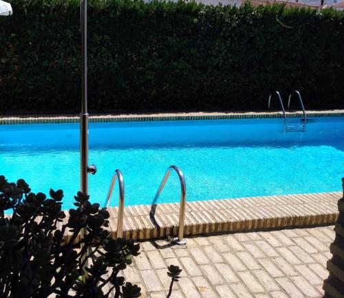 una piscina con agua azul y escaleras en ella en Hispalis villa en Matalascañas, en Matalascañas