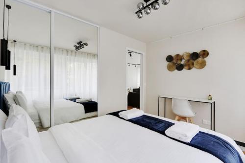 - une chambre blanche avec 2 lits et un miroir dans l'établissement Appartement Cosy pour 4 à La Villette - Paris, à Paris