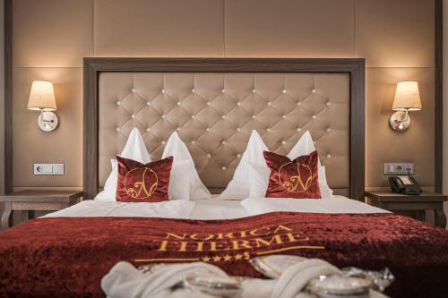 a hotel room with a large bed with red pillows at Hotel Norica - Thermenhotels Gastein mit dem Bademantel direkt in die Therme in Bad Hofgastein