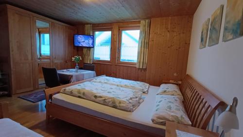 a bedroom with a bed and a table and windows at Gästehaus Lutz in Mellau