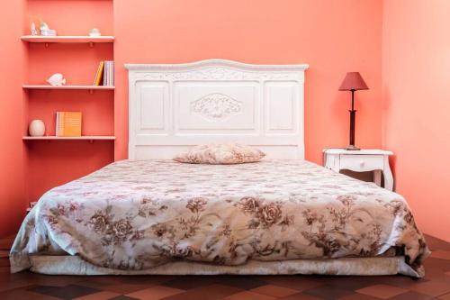 Schlafzimmer mit einem Bett mit einem weißen Kopfteil und orangefarbenen Wänden in der Unterkunft Noli centro, Ampia Casa stile Kinfolk + Parcheggio in Noli