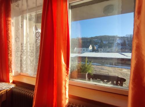 a window with a red curtain and a view at privat kobr in Rokytnice nad Jizerou
