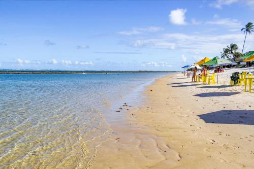 a beach with yellow tables and chairs and the water at Villa das Águas - Praia do Saco - OT in Estância