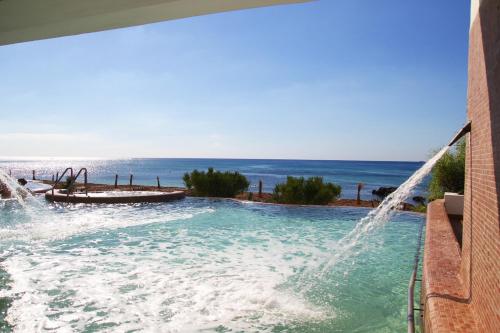 a swimming pool with a water slide and the ocean at Hotel Bel Azur Thalasso & Bungalows in Hammamet