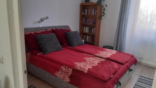 a red bed in a bedroom with a book shelf at Veronika Apartment in Székesfehérvár