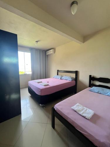 two beds in a room with pink sheets at Adialas Tour Angra dos Reis! in Angra dos Reis