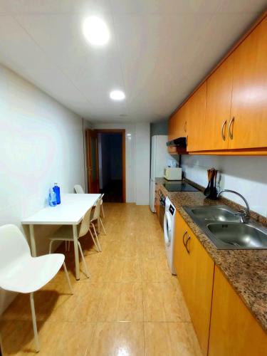 a kitchen with a sink and a table with chairs at Precioso piso in Catarroja