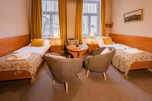 a hotel room with two beds and a table and chairs at Penzion Věžička in Lázně Bělohrad