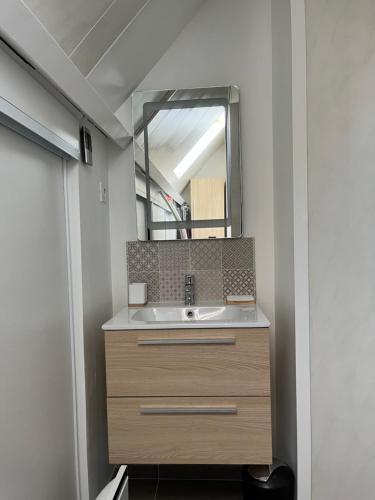 une salle de bain avec un lavabo et un miroir dans l'établissement Maison à 700m de la plage, à Courseulles-sur-Mer