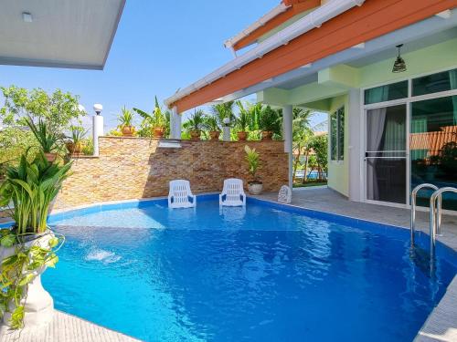 a swimming pool with two chairs in front of a house at Tina's Living Paradise - Guesthouses with private pool, 5 min to beach in Rayong