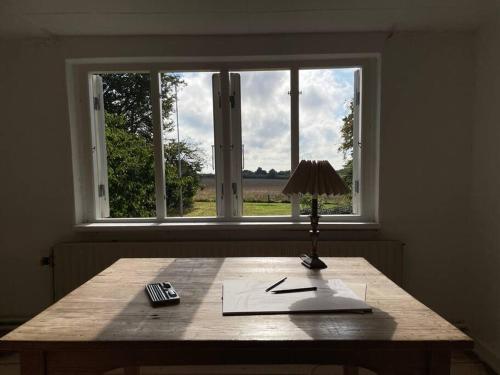 a table in front of a window with a lamp at Havlykkegaard - en unik gammel dame ved Østersøen in Idestrup