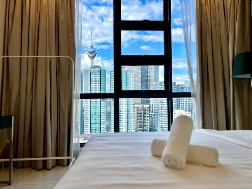 a white bed with a view of a city skyline at Eclipse Suites Robertson Bukit Bintang in Kuala Lumpur