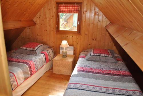 2 camas en una cabaña de madera con ventana en Gites Les Rainettes, en Vienne-en-Bessin