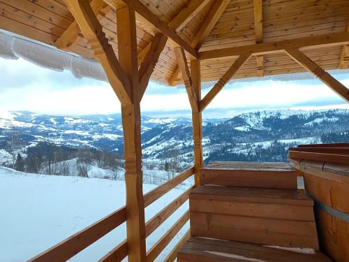 a view from the inside of a wooden cabin with snow covered mountains at Cabana Trif in Horea