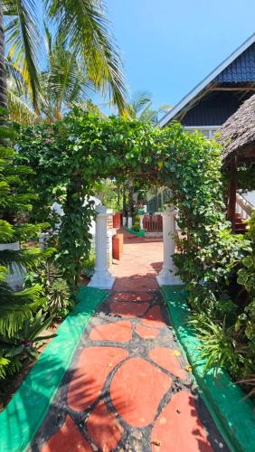 a garden with an arch with a stone walkway at Villa Buerk Serena Suite Bed & Breakfast, Wi-Fi, Pool in Mombasa