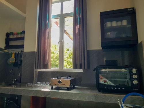 a kitchen counter with a microwave and a window at Happy house mirissa in Kamburugamuwa