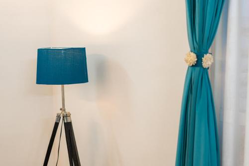 a floor lamp next to a blue curtain at Skystay Apartments in Lucknow