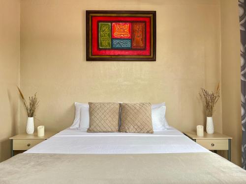 1 dormitorio con 1 cama blanca y una pintura en la pared en Casa Tatich AC near Guanacaste Airport, en Liberia