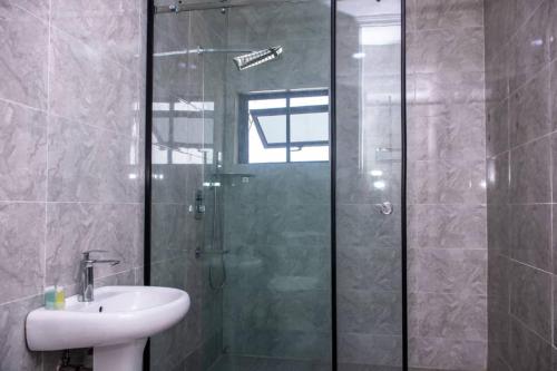 ein Bad mit einer Glasdusche und einem Waschbecken in der Unterkunft HASB APARTMENTS in Lagos