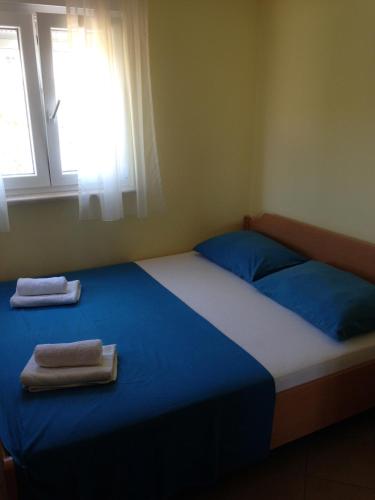a bedroom with a bed with blue sheets and a window at Novalja Zrce Apartment in Novalja