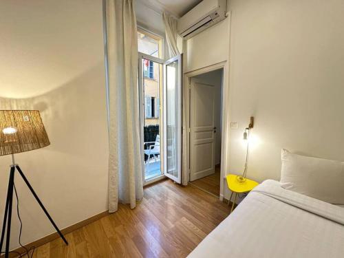 een slaapkamer met een bed en een deur naar een balkon bij Joli 2 pièces bien placé avec clim à 300m de la plage in Nice