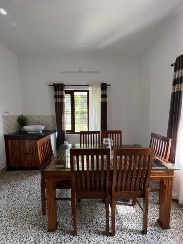 een eetkamer met een glazen tafel en stoelen bij Puthenveettil in Kottayam