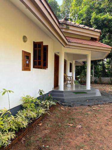 een klein wit huis met een bank op de veranda bij Puthenveettil in Kottayam