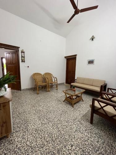 een woonkamer met meubilair en een plafondventilator bij Puthenveettil in Kottayam