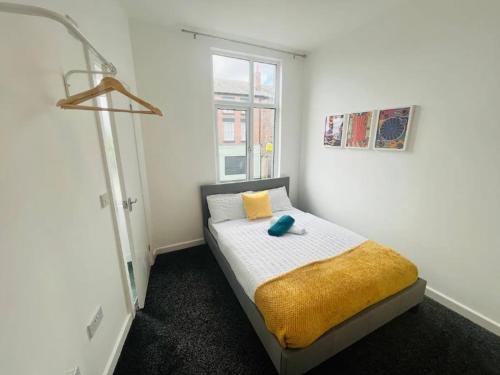 a bedroom with a bed with a yellow blanket and a window at Comfy Stylish 1BD Apt near Transport Links in Liverpool