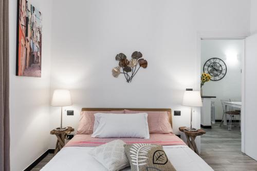 sypialnia z łóżkiem z białymi ścianami i 2 lampami w obiekcie ACQUARIO 5 Minuti, FREE A-C, Wifi & Netflix ''City Center'' by TILO w Genui