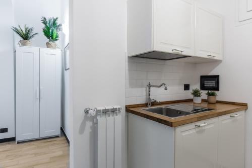 una cucina bianca con lavandino e frigorifero di ACQUARIO 5 Minuti, FREE A-C, Wifi & Netflix ''City Center'' by TILO a Genova