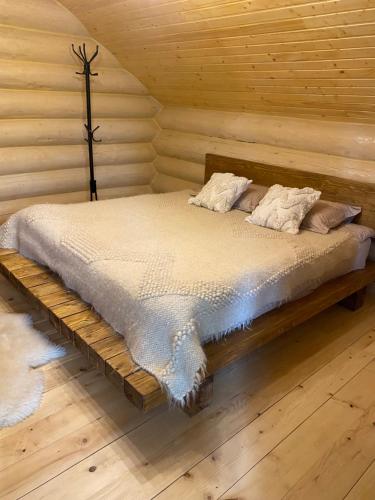 a bed in a cabin with a wooden wall at SevenHills chalet in Yablunytsya