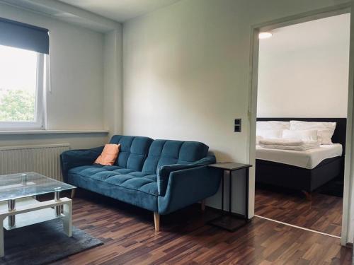 ein Wohnzimmer mit einem blauen Sofa und einem Bett in der Unterkunft Linz Central Apartment in Linz