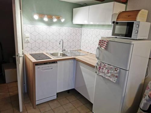 Il comprend une petite cuisine équipée d'un réfrigérateur blanc et d'un four micro-ondes. dans l'établissement Maison terrasse Port Leucate Hawaï 2, à Port-Leucate