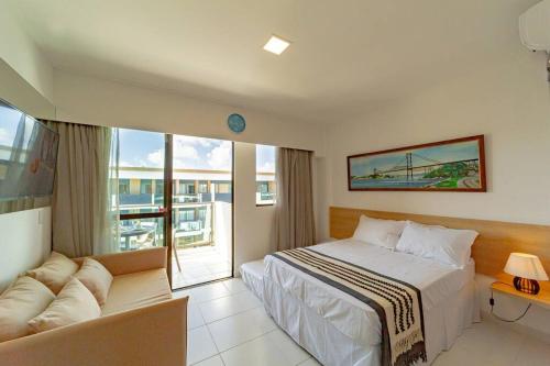 una camera d'albergo con un letto e un divano di Flat Luxo na praia de Muro Alto - Makia Experience a Porto De Galinhas