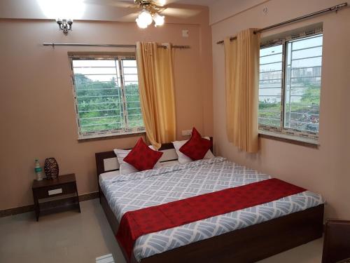 a bedroom with a bed with red pillows and windows at LOTUS APARTMENTS HOTEL in kolkata