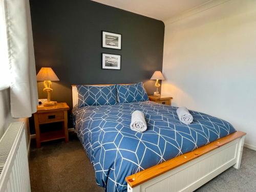 Bungalow33 Benllech في ينليش: غرفة نوم مع سرير مع لحاف أزرق