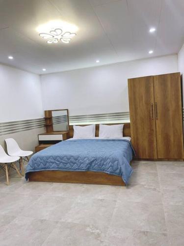 1 dormitorio con 1 cama grande y armarios de madera en T-House, en Can Tho