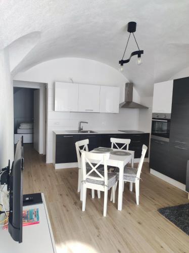 a white kitchen with a white table and chairs at Casa vacanza azzurra Lavarone in Lavarone